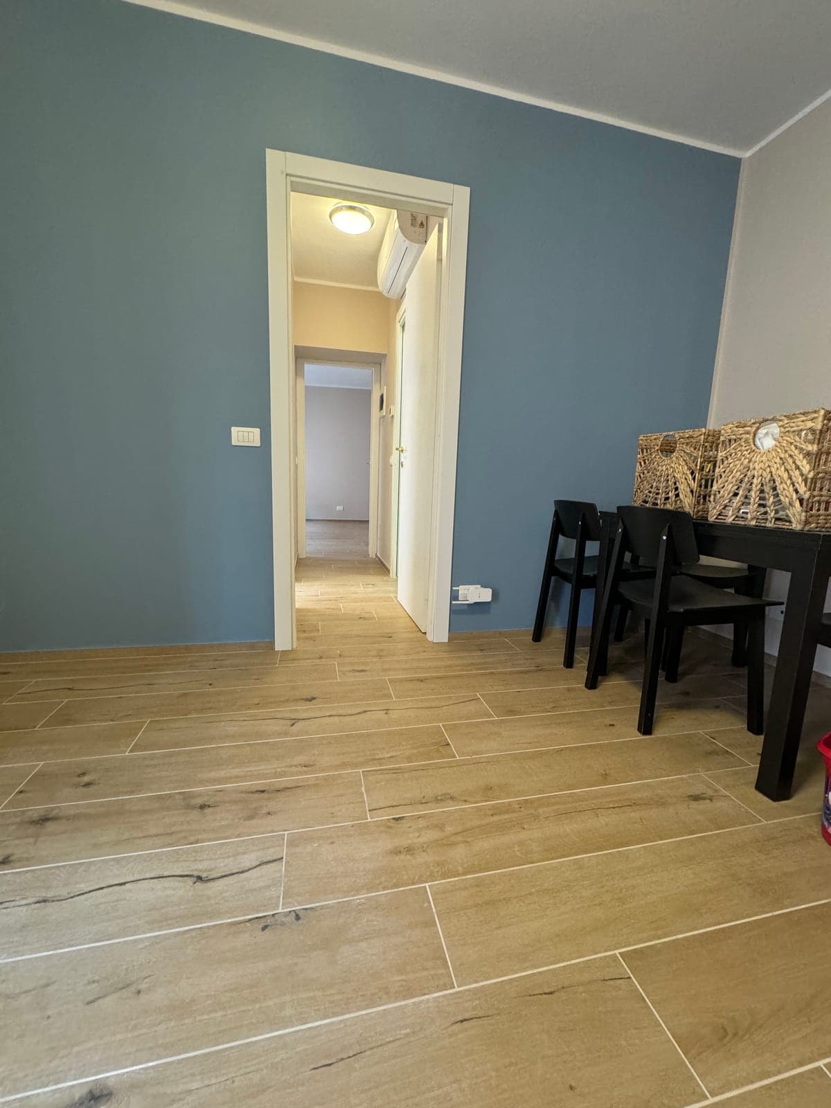Soggiorno con parete tinteggiata in blu e pavimento effetto legno